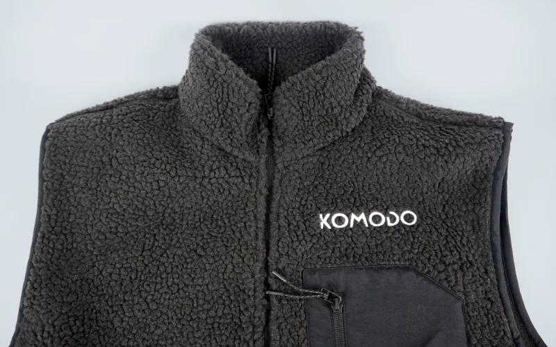 A black fleece vest with a high collar and a zippered pocket, featuring the brand name 