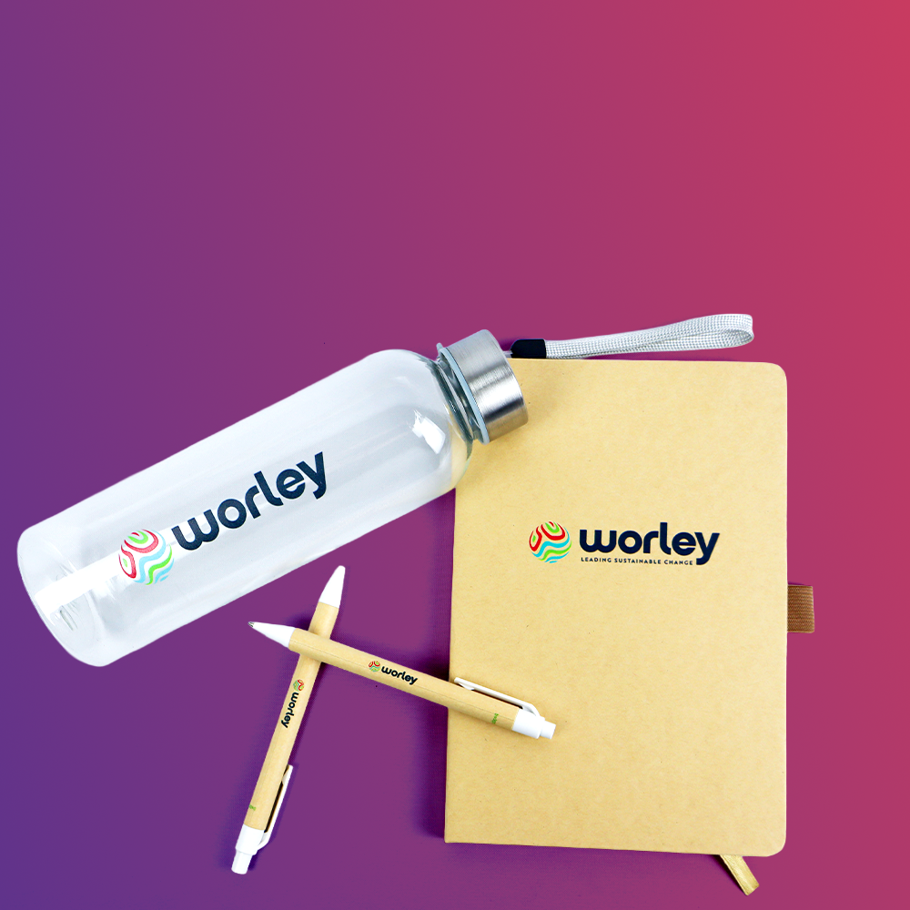 A glass water bottle, a brown notebook, and two pens (one green and one white), all featuring the logo of 