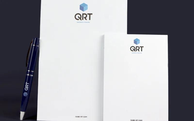 A pen and two notepads featuring the logo 