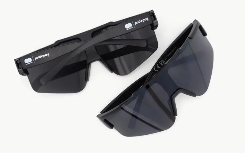 Two pairs of black sunglasses, one partially overlapping the other, featuring a logo on the side.