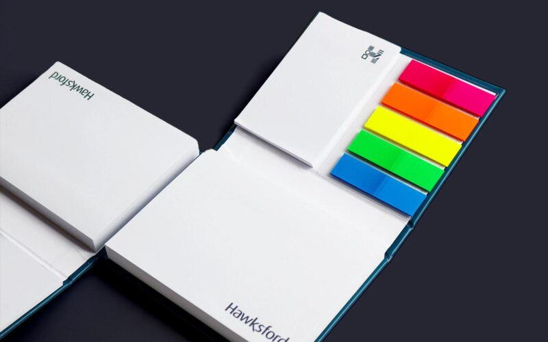 A set of notepads and sticky notes in various colors, with branding for 