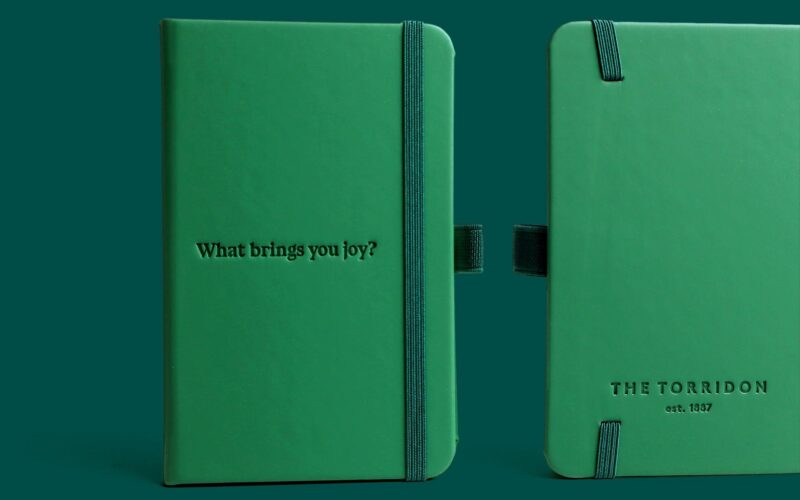 A green notebook featuring the embossed text 