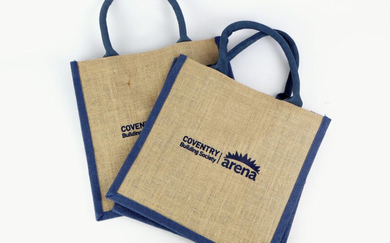 Two burlap tote bags with blue handles and printed logos for 