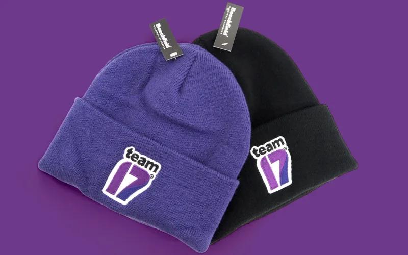 Two knit beanies, one purple and one black, each featuring a 