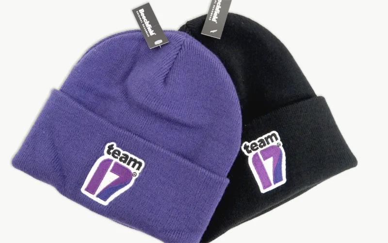Two beanie hats: one purple and one black, both featuring the logo 