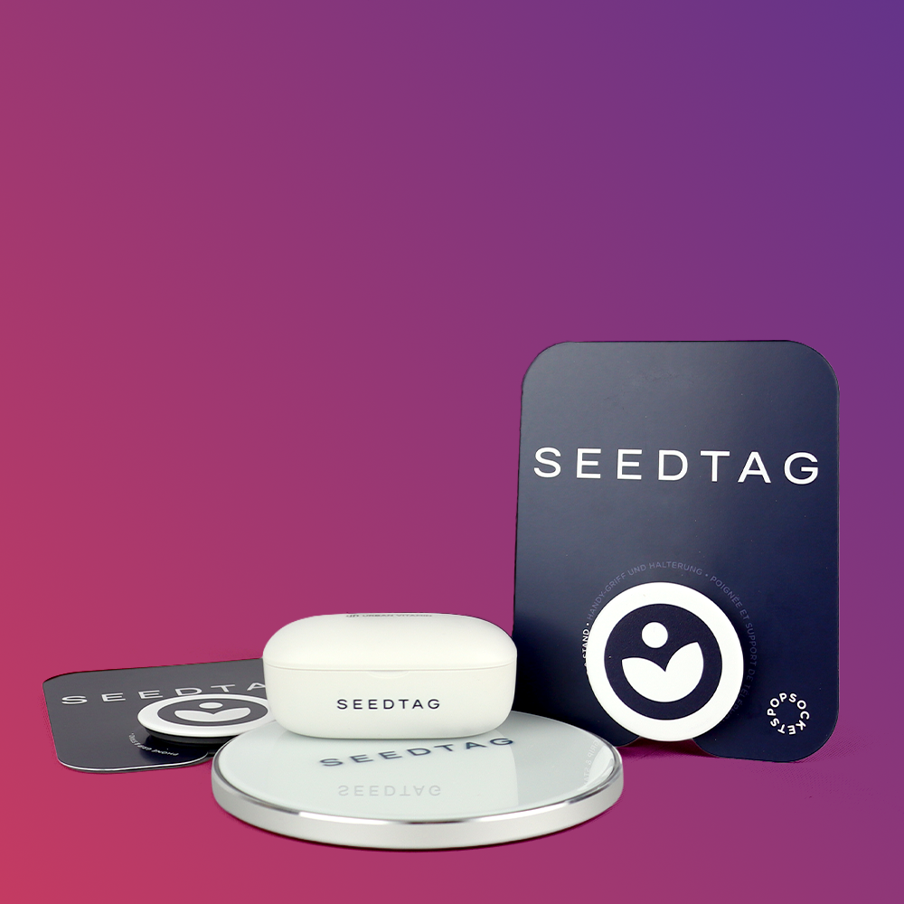A white SEEDTAG device, a circular mirror, and two black cards with the SEEDTAG logo and text on a gradient purple background.