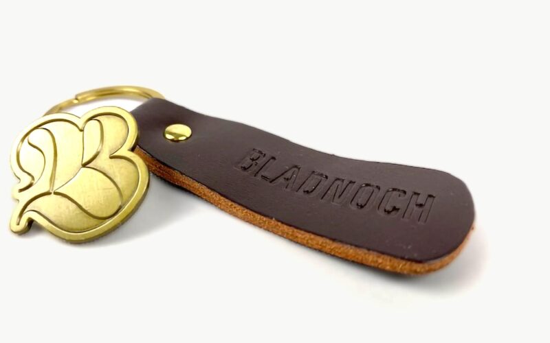 A brown leather keychain with the embossed word 